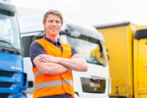 worker in orange safety vest in front of delivery trucks
