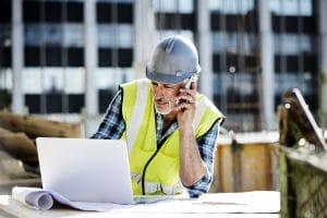 Contractor on job site searches for Cyber Liability Insurance on a laptop